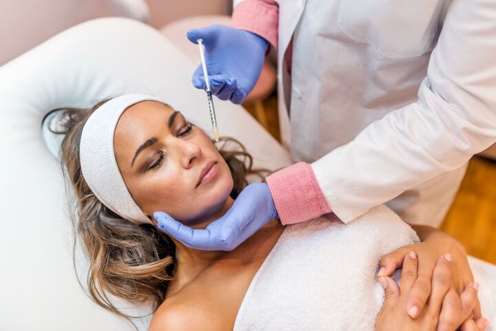 woman receiving an injection of dermal fillers in her cheek 