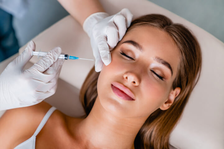 woman receiving an injection of dermal fillers in her face