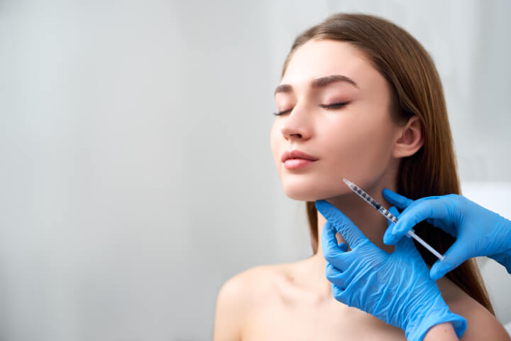 woman receiving an injection of dermal fillers in her face preformed by a medical doctor 