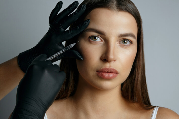 woman receiving an injection of dermal fillers in her face by a professional medical doctor
