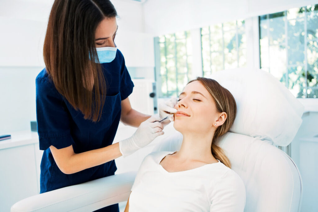 professional cosmetic doctor injecting a botox injection in a young woman's mouth 